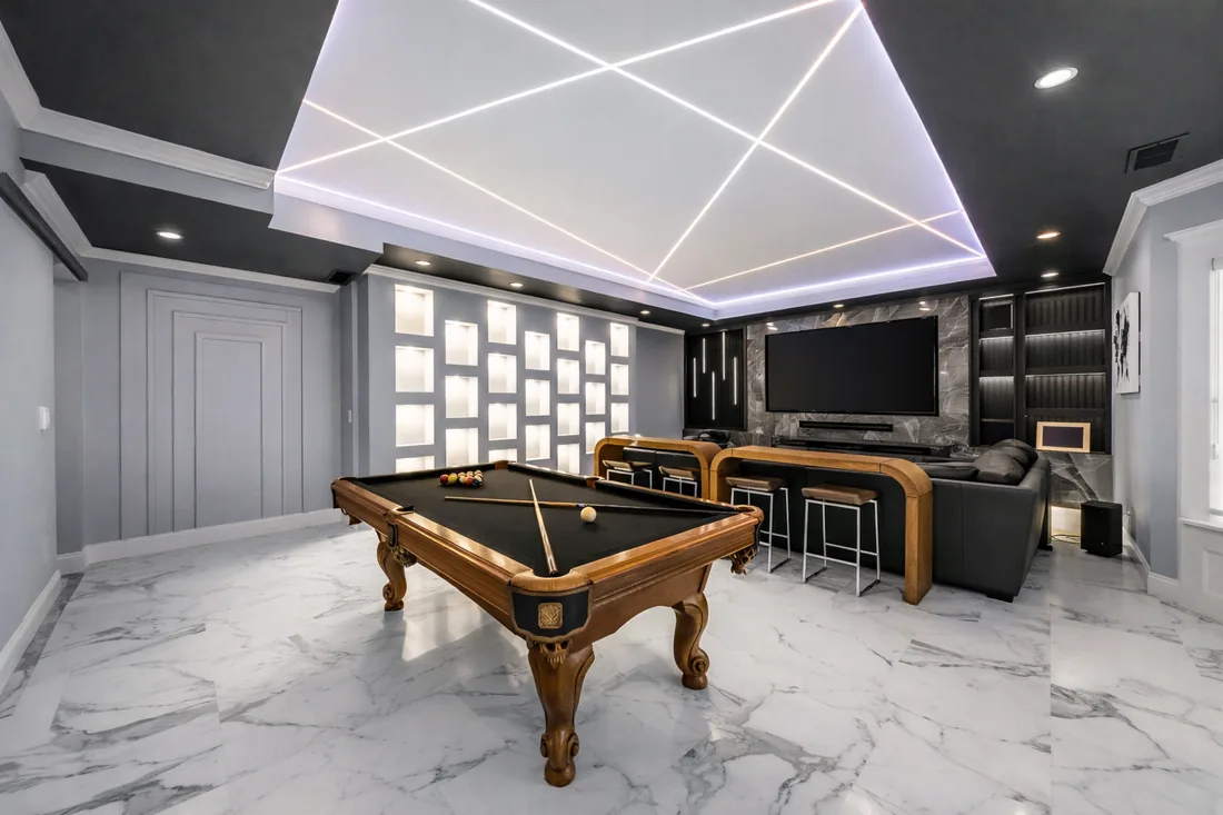 Finished basement games room under a lit geometric ceiling